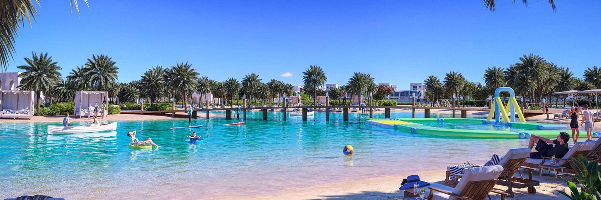 The lagoon beach at DAMAC Lagoons with swimmers, floats and the water-slide structure, from the developer's brochure