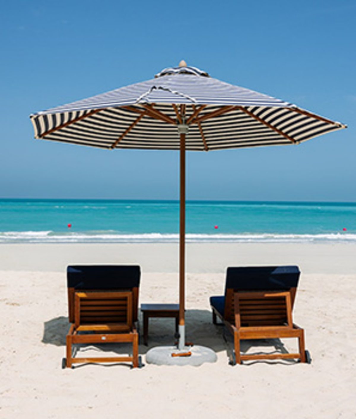 One umbrella and two loungers on the sand at Mamsha Beach, the sea behind