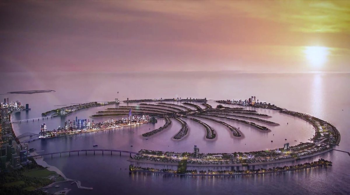 The whole of Palm Jebel Ali at sunset from the air, fronds lit, the Dubai coast to the left — a frame of Nakheel's own film