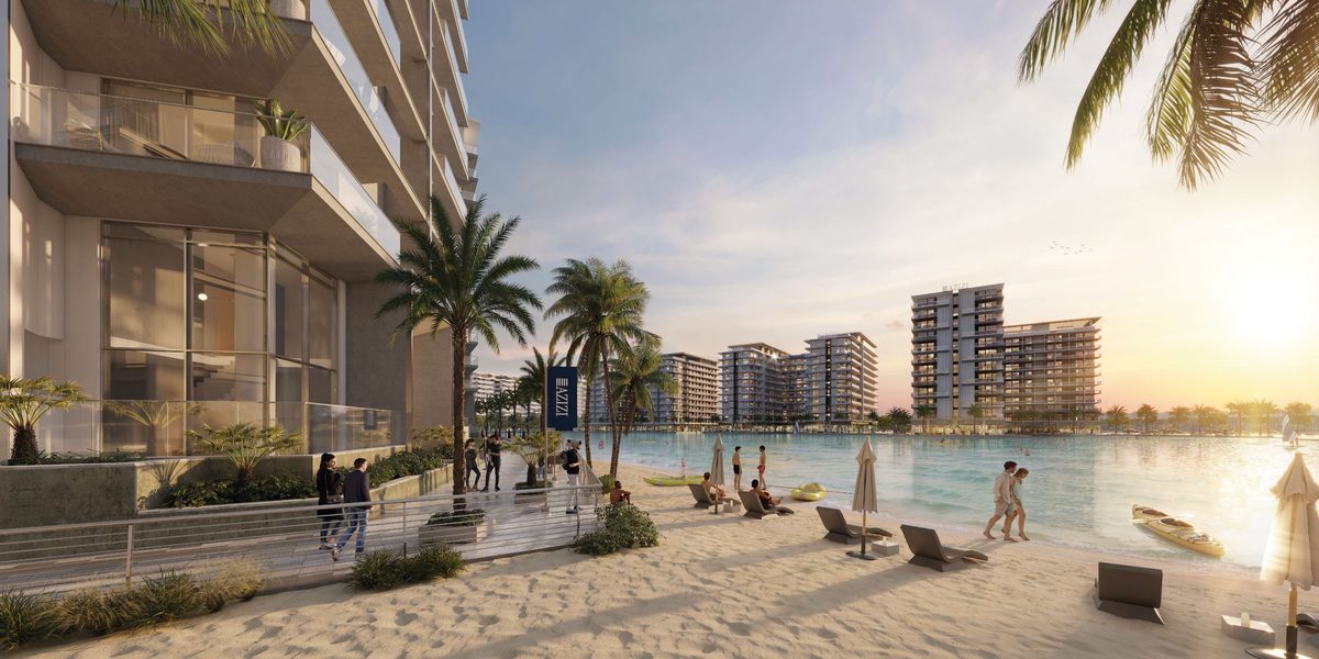 The lagoon beach at Azizi Venice at sunset, palms and loungers, mid-rise blocks across the water